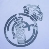 Remera celeste con cuello redondo y estampado rectangular negro con el logo del Real Madrid en el pecho.