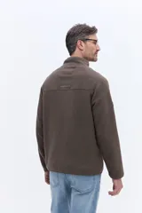Buzo de polar color marrón con cuello alto y cierre frontal parcial. Presenta un bolsillo frontal con cierre en contraste de color y mangas largas.