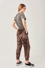 Pantalón tipo babucha de terciopelo con estampado de leopardo en tonos marrón y negro. Presenta cintura elástica y puños ajustados en los tobillos.