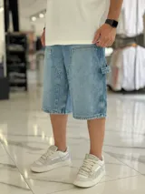 Bermuda de jean estilo carpintero, color celeste, con bolsillos laterales amplios, presilla para herramientas y diseño amplio de corte oversize.