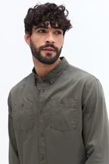 Camisa de gabardina color verde militar con efecto stone wash, doble bolsillo frontal con botón y fit regular.