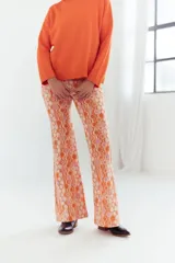 Pantalón de corte acampanado con estampado geométrico en tonos naranja, rosa y blanco.