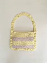 Cartera tipo shoulder bag tejida a crochet en hilo de algodón, con diseño a rayas en tonos de rojo y rosado, y detalles de volados en los bordes y la manija de hombro.
