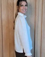 Camisa de manga larga con estampado de rayas verticales en tonos crudo y beige. Presenta cuello alto con volados, cierre frontal con botones dobles y puños con volados.