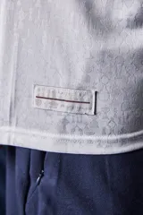 Camiseta de fútbol Umbro del Club Nacional de Football, modelo Home 2026. Diseño blanco con cuello en V, detalles en azul y rojo en el cuello y las mangas, y patrón en tejido jacquard. Incluye el logo de Umbro, el escudo del club y el sponsor antel en el pecho.