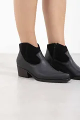 Botineta de cuero negro mate con inserciones de gamuza en el talón, punta cuadrada y tacón de bloque. Cuenta con cierre lateral interno.