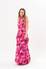 Vestido largo fucsia con estampado abstracto, cuello halter con abertura en forma de lágrima y volados en la falda.