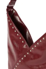 Cartera tipo hobo de cuero sintético negro con acabado brillante, decorada con tachuelas metálicas plateadas a lo largo de la correa y en la costura frontal diagonal.