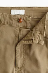Pantalón tobillero de corte bootcut en lona de algodón, color marrón, con cintura estándar, bolsillos delanteros y pliegues marcados.