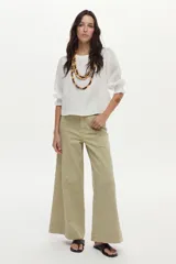 Blusa de lino blanca con escote redondo y mangas cortas abullonadas con detalles de volados en los puños.