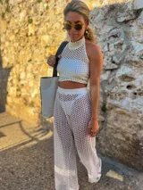 Top blanco tejido calado con cuello halter y corte crop.