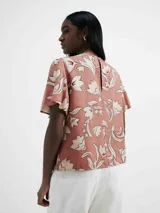 Blusa color salmón con estampado de flores blancas, de mangas cortas con volados y cuello redondo.