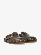 Zueco de cuero liso negro con plantilla anatómica forrada en gamuza, hebilla ajustable de estilo western en metal envejecido y tachas metálicas en el contorno.