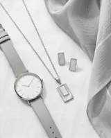 Set de joyería compuesto por un collar con dije rectangular y un par de aros a juego, ambos con incrustaciones de nácar y estructura de acero inoxidable.