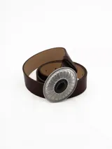 Cinto de cuero negro con hebilla ovalada de metal plateado con diseño estriado y piedra central negra.