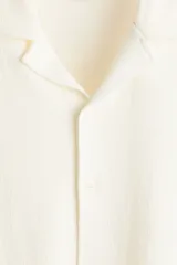 Camisa de manga corta color blanco hueso, de punto jacquard en mezcla de algodón, con cuello abierto y cierre frontal de botones.
