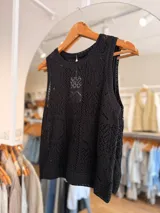 Musculosa negra tejida con diseño calado de patrones geométricos y florales, sin mangas y con escote redondo.