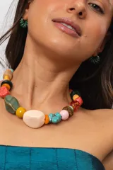 Collar corto compuesto por cuentas de cerámica, resina, piedras naturales y madera en tonos celestes, turquesas, verdes, marrones y beige, con cierre ajustable de cadena y mosquetón.