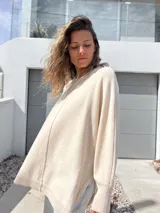 Sweater oversize de tejido de punto color crudo, con cuello redondo, manga larga con puños acanalados y detalle de costura vertical central. Presenta un diseño holgado con aberturas laterales en el ruedo.