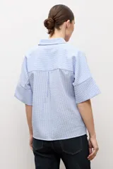 Camisa celeste con rayas blancas, de manga corta y cuello camisero.