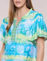 Blusa de rayón en tonos turquesa y verde, con cuello en V con detalles bordados, mangas cortas amplias y diseño estampado con motivos florales y geométricos.
