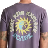 Remera Roark de manga corta en color violeta, con diseño gráfico pequeño en el pecho que representa un sol y olas con la inscripción 'Roark'.