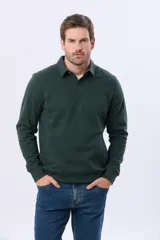 Buzo de felpa color verde oscuro, con cuello tipo polo, cierre frontal parcial con botones y bolsillos laterales. Presenta puños y ruedo acanalados.