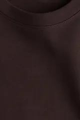 Remera de corte holgado confeccionada en punto interlock de mezcla de algodón pesado, con cuello redondo, hombros caídos y mangas cortas que llegan por encima del codo.