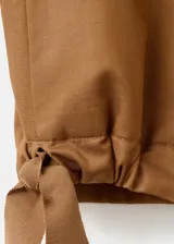 Chaqueta de diseño corto en tono tostado, confeccionada con mezcla de lyocell, algodón y lino. Presenta cuello redondo, mangas largas abullonadas, elásticos en los laterales y cierre frontal de botonadura visible.