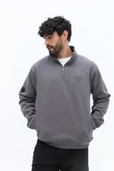 Buzo de algodón color terracota, con cuello alto y cierre parcial frontal. Presenta puños y cintura ajustados, bolsillos laterales y un pequeño logo bordado en el pecho.