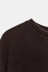 Top blanco de tejido rústico, con cuello redondo y mangas cortas amplias. Bajo recto.