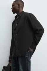 Camisa de corte regular fit confeccionada en tejido de algodón con textura de cuadrillé. Presenta cuello solapa, manga larga con puños abotonados y cierre frontal mediante botonadura.