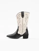 Bota corta de cuero sintético color negro y blanco, con punta fina y bordados decorativos.