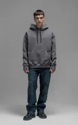 Hoodie oversize color gris oscuro, confeccionado en frisa premium con textura gamuzada. Presenta capucha ajustable con cordones personalizados, bolsillo frontal tipo canguro y puños con abertura para el pulgar.