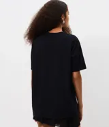 Remera negra de algodón con cuello redondo, mangas cortas y estampa frontal de la saga Harry Potter con ilustración nocturna del castillo de Hogwarts y el texto First Years This Way.