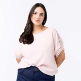 Camiseta rosada con cuello redondo y mangas cortas holgadas que presentan detalles de bordado y macramé.