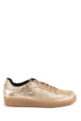 Championes de estilo urbano en color dorado con acabado brillante, cordones al tono y suela de goma color caramelo.