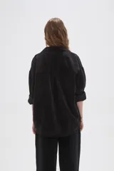 Camisa de pana negra con cuello clásico, cierre frontal de botones y bolsillo en el pecho.