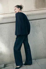 Blusa de crepé de gasa color azul marino, con cuello mao y abertura frontal con tiras finas. Presenta un diseño holgado con volados verticales en el frente, mangas largas tipo globo con corte raglán y puños elásticos con volados.