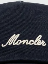 Gorra de baseball Moncler color azul marino, con visera curva y detalle de borde en color crema. Presenta el logo de la marca bordado en la parte frontal en color crema.