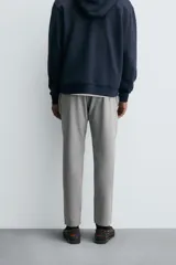 Pantalón de corte slim fit confeccionado en tejido elástico, con cintura elástica, cierre frontal con cremallera y botón, bolsillos laterales y bolsillos traseros de vivo.