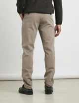 Pantalón de vestir verde oliva, de corte slim fit, sin pinzas, con bolsillos laterales y traseros. Se ajusta a la cintura con cinturón de cuero marrón.