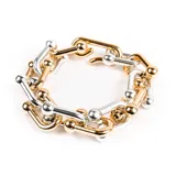 Pulsera de eslabones dorados y plateados con forma de U y detalle de bolitas en los extremos.