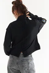 Buzo rústico marrón con cuello polera, mangas largas y calce boxy. Presenta costuras externas decorativas, puños acanalados y un bordado sutil en el pecho.