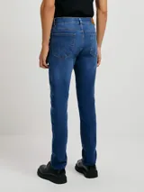 Pantalón de jean corte skinny, color azul medio, con diseño de cinco bolsillos y cierre frontal con botón y cremallera.