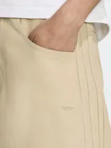 Bermuda color beige de corte ancho con tres líneas verticales a los costados y logo de la marca bordado en la pierna izquierda.