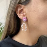 Aros colgantes con base circular rosa, detalle de strass y dije transparente con diseño abstracto celeste.