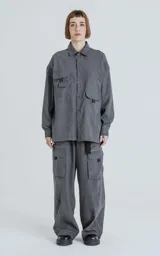Camisa de manga larga color grafito, estilo técnico con múltiples bolsillos delanteros con tapa y botones en cartera y puños. Presenta un calce oversize y está confeccionada en textil ligero y suave al tacto.