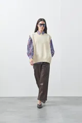 Chaleco tejido de punto con silueta relajada y diseño sin mangas. Presenta lazos laterales ajustables y cuello redondo.