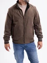 Campera reversible de estilo bomber, confeccionada en material tipo gamuza color marrón. Presenta cierre frontal, bolsillos laterales con cierre y puños y cintura de tejido elástico acanalado con detalles de líneas horizontales.
